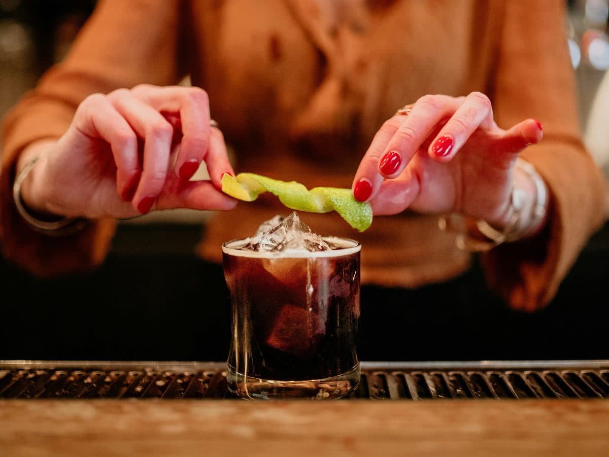 Bartender garnishing a craft cocktail with a citrus twist at a private event