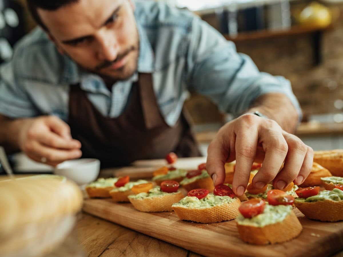 Personal chef topping fresh crostini by hand in a home kitchen